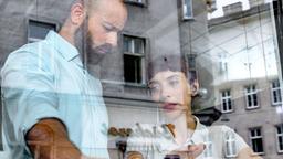 Dr. Pielach (Ruth Brauer-Kvam, rechts) vertraut Dr. Hoffmann (Anton Noori) im Café ein schwerwiegendes Geheimnis an.