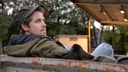 Daniel Becker (Jordan Dwyer) wartet an einer Tankstelle auf eine Mitfahrgelegenheit.