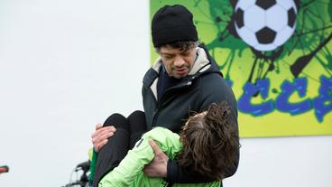 Frank Baumann (Carlo Ljubek) trägt seinen verletzten Sohn Hannes Baumann (Mikke Rasch) vom Platz.