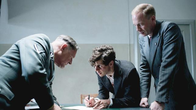 Bild: SWR/Lucky Bird Pictures GmbH/Bernd Schuller Georg Elser (Christian Friedel) erklärt Nebe (Burghart Klaußner, li.) und Heinrich Müller (Johann von Bülow, re.), wie er die Bombe gebaut hat.