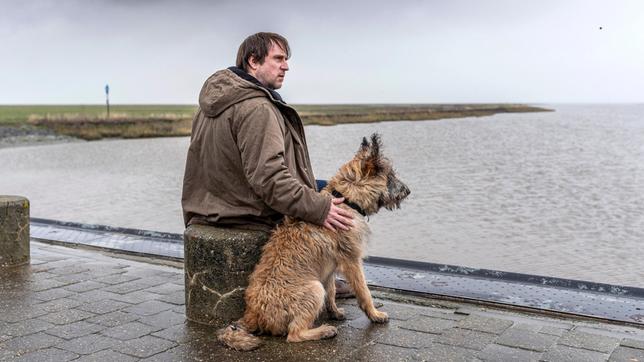 Sörensen (Bjarne Mädel) mit Hund Cord vor dem nordfriesischen Wattenmeer.