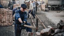 Tommy (David Schütter) hackt Steine auf der Baustelle an der Stalinalle.