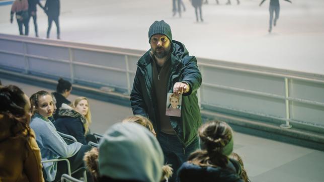 Dennis Eden (Stephan Zinner) befragt in der Eishalle Jugendliche und zeigt ihnen das Foto von Laura.