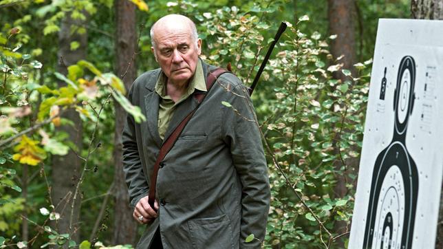 Bild: rbb/Oliver Feist Der Bürgermeister von Falkenhain, Roland Seedow (Hanns Zischler), ein leidenschaftlicher Jäger, beäugt die Schießübungen seiner Bürger im Wald mit Argwohn.