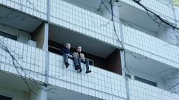 Klaus (Ben Becker) und Henry (Anton von Lucke, re.) sitzen auf der Balkonbrüstung; Henry will sich um Saras Beerdigung kümmern.