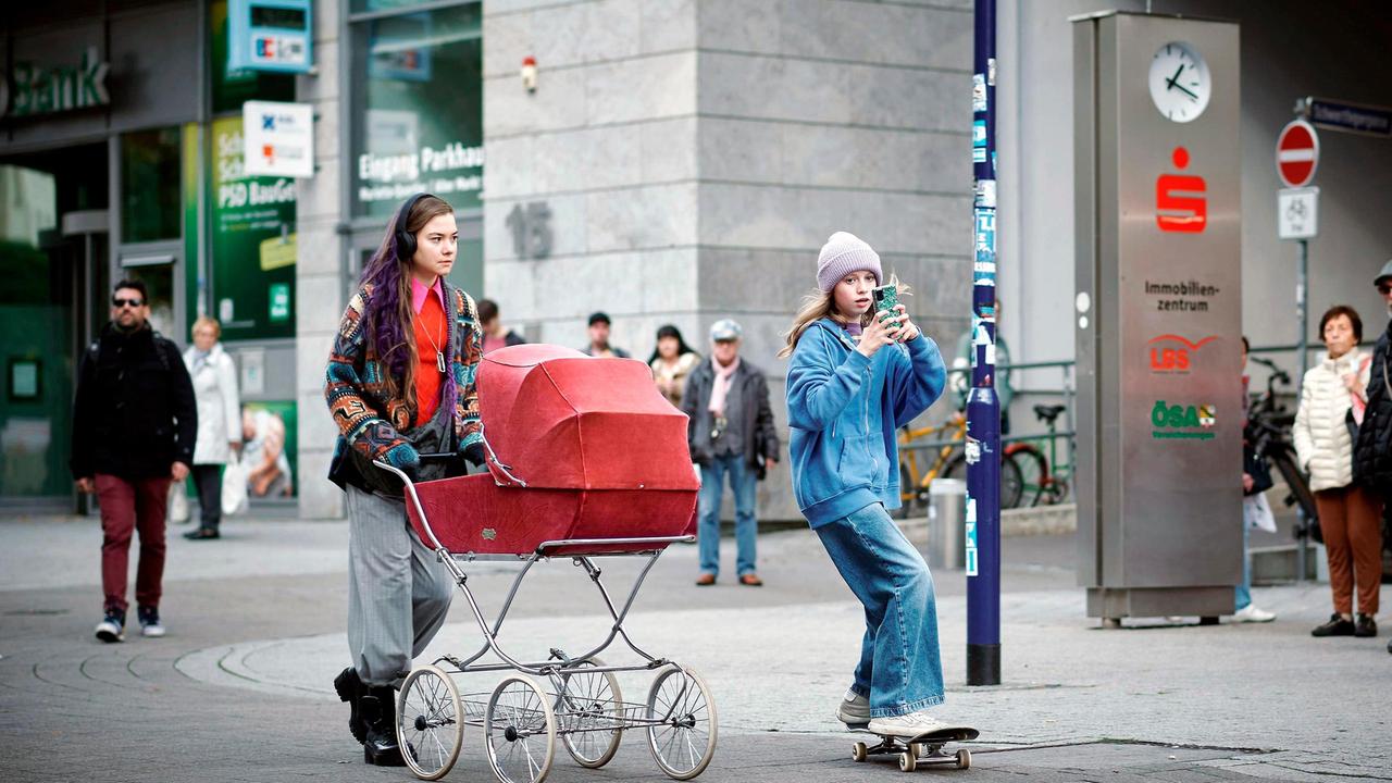 LANA STOKOWSKY (Hannah Schiller) geht mit ihrem Säugling im Kinderwagen spazieren.