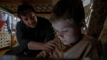 Ronny (Johann Barnstorf) ist traurig, weil seine Mutter noch nicht angerufen hat. Matthias (Thomas Schubert) überredet ihn seine Geschenke auszupacken.