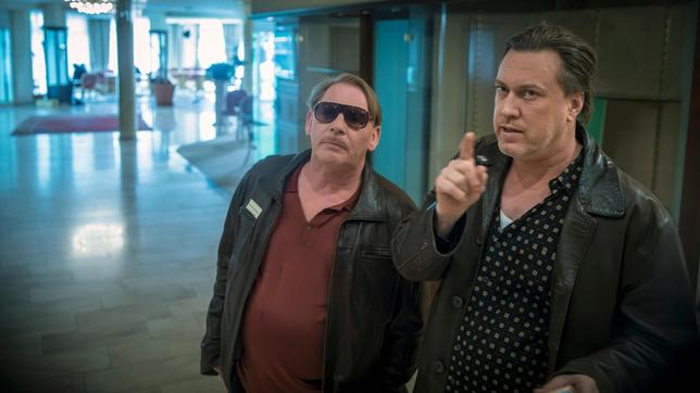 Bild: WDR/Tom Trambow Die Kommissare Franz Mitschowski (Nicholas Ofczarek, r) und Markus Rettenbach (Ben Becker, l) gehören zu den Ermittlern, die der Polizeipräsident in ein leerstehendes Tagungshotel geladen hat. Sie sollen als Team eine Mordserie stoppen.