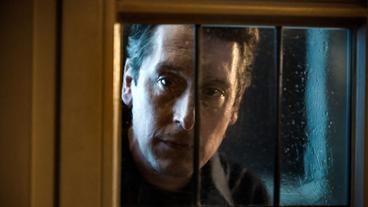 Dr. Jens Jacoby (Hans Löw) schaut durch ein Fenster in ein Lokal.