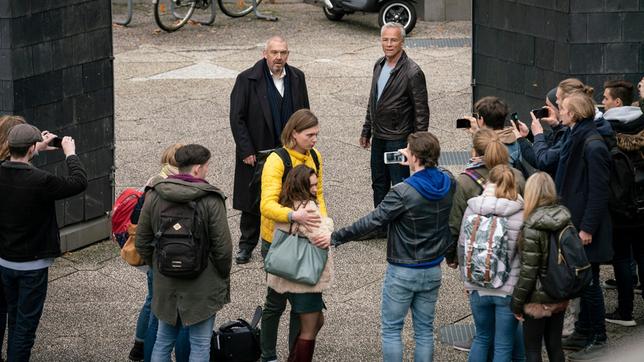 Freddy Schenk (Dietmar Bär, hinten Mitte) muss sich rechtfertigen. Max Ballauf (Klaus J. Behrendt, hinten rechts) sieht zu, wie sein Kollege beschuldigt wird, Nadine Wilcke (Emma Drogunova, vorne) auf dem Schulhof belästigt zu haben. Ihr Freund Lennart (Moritz Jahn) nimmt sie in Schutz, während andere Schüler*innen mit den Handys filmen.