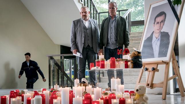 Freddy Schenk (Dietmar Bär, l) und Max Ballauf (Klaus J. Behrendt, r) an dem Ort, wo Kollegen in ihrer Dienststelle an den getöteten Beamten erinnern.