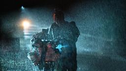 In der regnerischen Nacht kämpft Foxy sich mit seinem Fahrrad die Solitude hinauf, als sich ein Wagen von hinten nähert.
