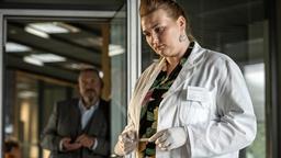 Laborantin Anna Keller (Sophie Roeder) soll bei einem Verdächtigen im Verhörraum eine Speichelprobe nehmen. Kommissar Freddy Schenk (Dietmar Bär) schaut zu.