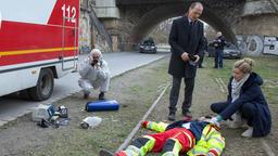 Leo Winkler (Cornelia Gröschel, re.) und Peter Michael Schnabel (Martin Brambach) am Tatort an den Elbbrücken, vor ihnne liegt der im Einsatz ermordete Rettungssanitäter Tarik Wasir (Zejhun Demirov).