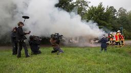 Am "Tatort"-Set: Tonteam und Kamerateam um Alexander Fischerkoesen vor Bennys Haus, im Hintergrund löscht die Feuerwehr das brennende Auto.