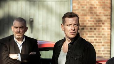 Bild: WDR/Martin Valentin Menke Stefan Krömer (Gerdy Zint, rechts) muss sich den Fragen der Polizei stellen. Kommissar Freddy Schenk (Dietmar Bär, links) hört, was der Bauarbeiter zu sagen hat. Im Hintergrund steht dessen Sportwagen.