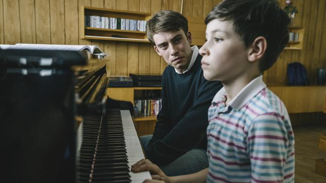 Anton Steiner (Lukas B. Amberger, links) gibt Stefan Kamann (Carlo Kalajzic) Klavierunterricht und bittet ihn genau zuzuhören.
