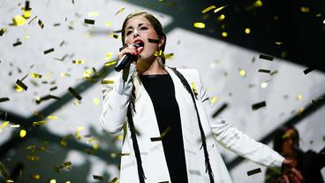 ESC-Kandidatin Ann Sophie singt in ein Mikrofon, während goldenes Konfetti auf sie herunter regnet.