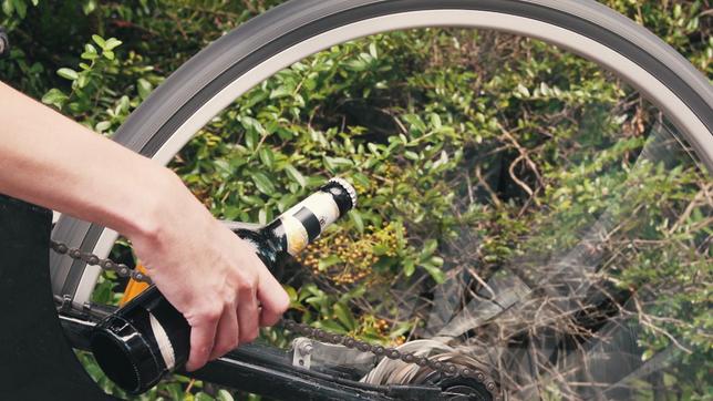 Eine Radler-Flasche wird an ein drehendes Rad gehalten
