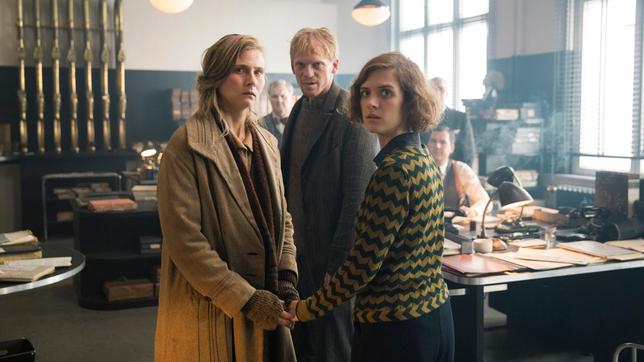 Bild: X Filme Creative Pool/ARD Degeto/WDR/Sky/Beta Film 2019/Frédéric Batier Erich (Pit Bukowski) taucht mit Charlottes (Liv Lisa Fries) Schwester Ilse (Laura Kiehne) im Polizeipräsidium auf und macht sie für die missglückte OP verantwortlich.