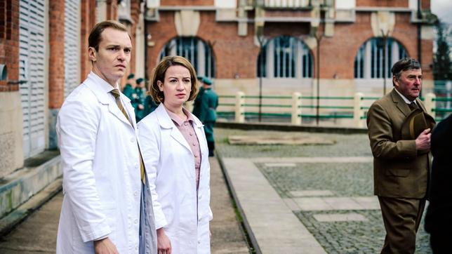 Bild: ARD/Stanislav Honzik Dr. Ella Wendt (Nina Gummich) und Dr. Alexander Nowack (Max Wagner) schauen entsetzt zum Humboldhafen - der erste Mauertote wird aus dem Wasser geborgen.