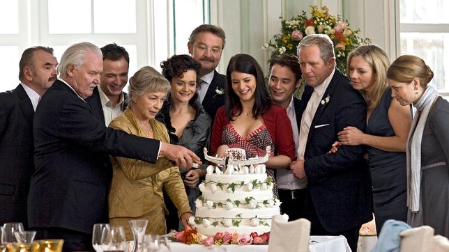 Gottfried und Hermine schneiden im Beisein der Hochzeitsgäste die Hochzeitstorte an.