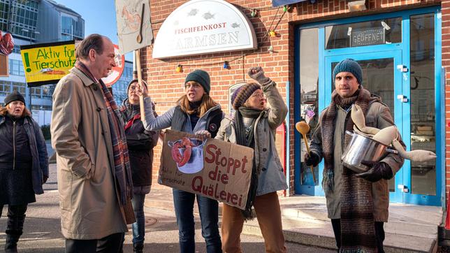 Bild: ARD/Georges Pauly Tierschützer blockieren das Geschäft von Fischhändler Harmsen: Markus Gellert (Herbert Knaup) trifft auf Gundula Mosbacher (Catherine Bode), Gesine Brunken (Anna Böttcher) und Thomas Zuhse (Oliver Wnuk), der sich den Demonstrantinnen angeschlossen hat.