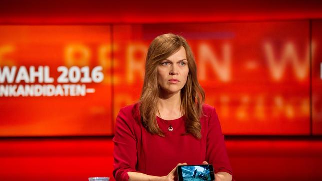 DIE STADT UND DIE MACHT: Susanne Kröhmer (Anna Loos) zeigt in der letzten TV-Debatte vor der Wahl das Handyvideo, das Degenhardts und KKs Auftragsmord beweist.