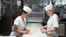 Alexandra (Julia Richter, re.) und Paula (Mariam Hage) am Fließband der Großbäckerei und scherzen über ein besseres Leben.