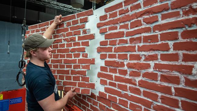 Bild: ARD/Thorsten Jander Foto von der Baustelle: Nick Matoschi vom Bühnenbau beim Anbringen der Klinker-Fassade.