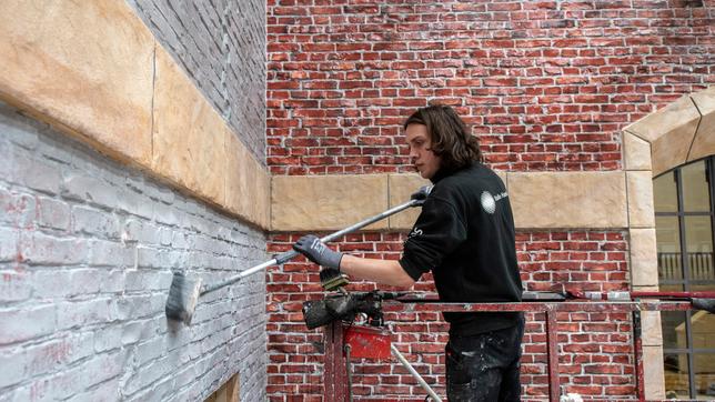 Bild: ARD/Thorsten Jander Foto von der Baustelle: Kulissenmaler Winston Ziller beim Patinieren der Klinker-Fassade.