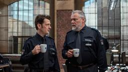 Daniel Schirmer (Sven Fricke) berichtet seinem Kollegen Helmut Husmann (Torsten Münchow) bei einer Tasse Kaffee von den Ereignissen im Museum.