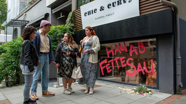 Harry Möller (Maria Ketikidou) und Nils Sanchez (Enrique Fiß) fühlen mit Sandra Freut (Nadja Zwanziger) und ihrer Tochter Alina (Dilara Aylin Ziem), die schlimmen Diskriminierungen ausgesetzt sind. Jemand hat die Schaufensterscheibe ihrer Boutique mit den Worten "Hau ab fette Sau" beschmiert.