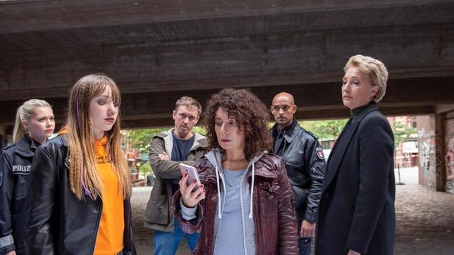 Bild: ARD/Thorsten Jander Minuten der Angst: Katharina von Stetten (Ruby M. Lichtenberg) spielt Harry (Maria Ketikidou) ein Video ihrer Schwester Melanie vor, die eine Bombe im Rucksack mit sich trägt. Jessy (Farina Flebbe), Piet (Peter Fieseler), Lukas (Patrick Abozen, 2.v.r..) und Frau Küppers (Saskia Fischer) können nur hoffen, dass sie die Anweisungen der Polizei befolgt, bevor ein furchtbares Unglück passiert.
