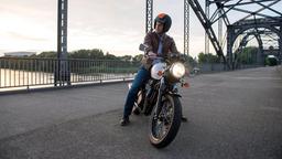 Robert Bargen (Julian Weigend) hält mit seinem Motorrad auf einer alten Elbbrücke.