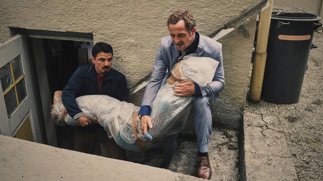 Erol (Ercan Karacayli) und Alfons Zischl (Maximilian Brückner) tragen die Leiche von Amadou raus.