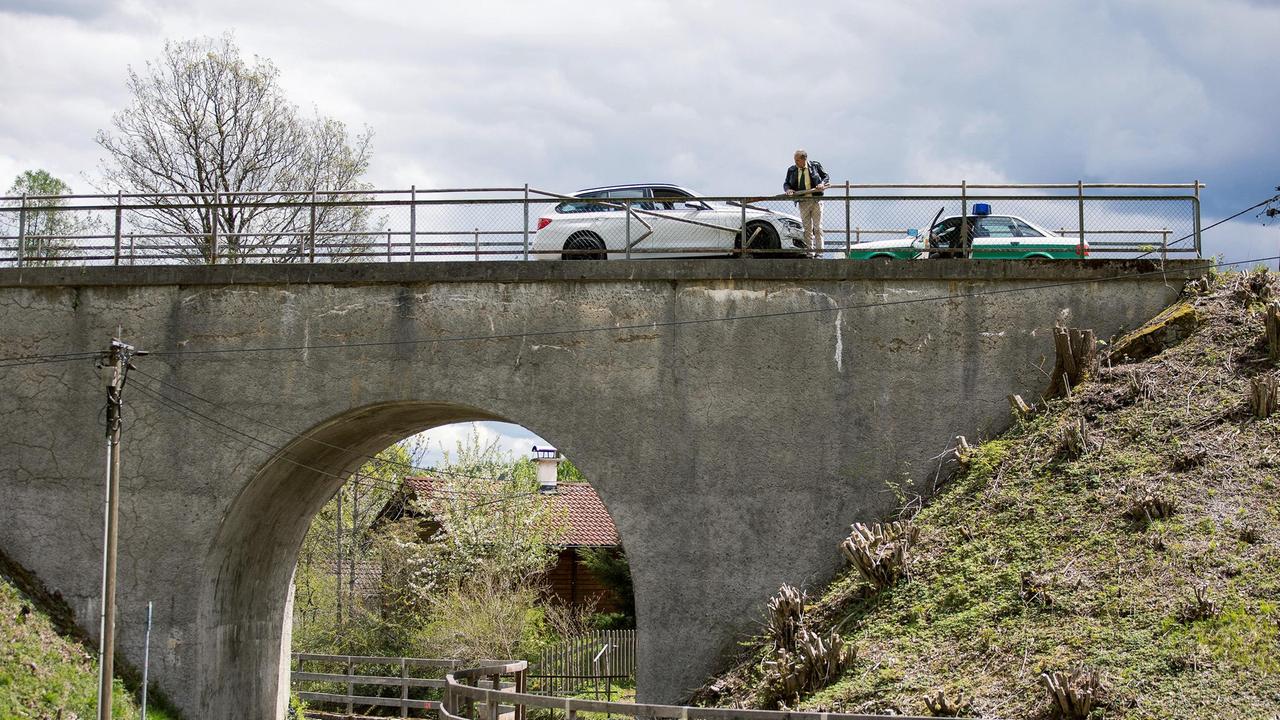 Auf einer Brücke im bayerischen Oberland entdecken Hubert (Christian Tramitz, o.) und Girwidz (Michael Brandner, im Polizeiauto) ein herrenloses Fahrzeug. Der Fahrer des Wagens Frank Giebel liegt tot am Fuß der Brücke.