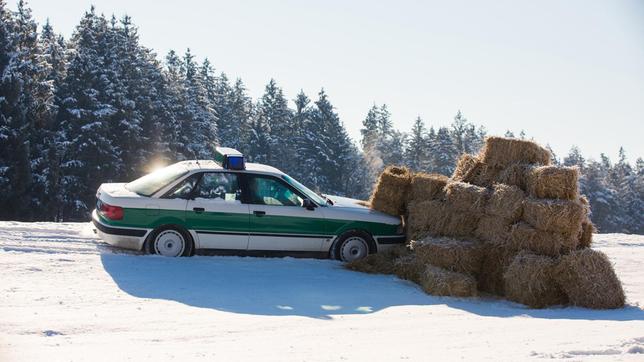 Bild: ARD/Kai Neunert Die Bremsen am Streifenwagen haben versagt, Hubert (Christian Tramitz) und Girwidz (Michael Brandner) landen mit dem Auto in einem Haufen aus Strohballen.