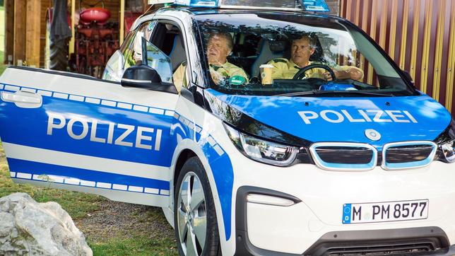Bild: ARD/TMG/Kai Neunert Hubert (Christian Tramitz) und Girwidz (Michael Brandner) warten im neuen, elektrischen Streifenwagen auf Riedls Meldung.