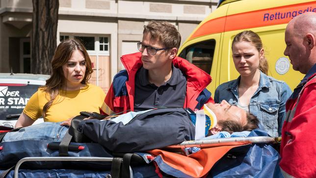 Bild: ARD/Jens-Ulrich Koch Als der Rettungswagen mit Elias (Stefan Ruppe, h.) eintrifft, haben Jasmin Hatem (Leslie-Vanessa Lill) und Louisa Neukamm (Llewellyn Reichman, r. mit Komparse) schon erfolgreich erste Hilfe geleistet. So dass sie den Patienten Norman Schlüter (Peter Sikorski) sofort ins Johannes-Thal-Klinikum bringen können.