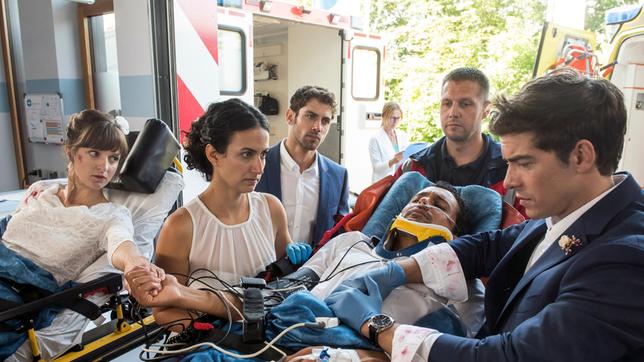 Bild: ARD/Paul-Ruben Mundthal Auf dem Weg zum Standesamt wurden Leyla (Sanam Afrashteh) und Ben (Philipp Danne) zu Ersthelfern - sie liefern Isabel (Lilly Marie Tschörtner) und Martin (Omar El-Saeidi) ins JTK ein (mit Roy Peter Link, 3.v.l. und Komparsen).