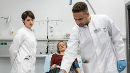 In aller Freundschaft - Die jungen Ärzte: Katja Witte (Caroline Scholze) wird von Dr. Moreau (Mike Adler) und Dr. Koshka (Katharina Nesytowa) untersucht.