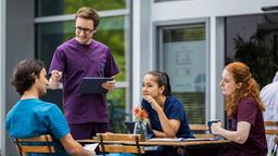 Die vier jungen Ärzte planen zwischen ihrem Krankenhausalltag ihre Feier zum einjährigen Jubiläum. Ivo hat sich für die Gruppe Vorschläge einfallen lassen, die nicht unbedingt den Geschmack aller treffen. (v.l.n.r. Ivo Maric (Jakob D'Aprile), Olli Probst (Arne Kertész), Sofia Galura (Olivia Papoli-Barawati), Tamar Hummel (Linda Kummer)).