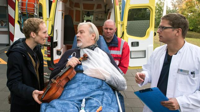Bild: ARD/Jens Ulrich Koch Dr. Elias Bähr (Stefan Ruppe) nimmt den Instrumentenbauer Hartmut Hoffmann (Andreas Leupold, M. mit Komparse, h.) im Johannes-Thal-Klinikum auf. Er ist in Begleitung seines Sohnes Lenny (Manuel Zschunke).
