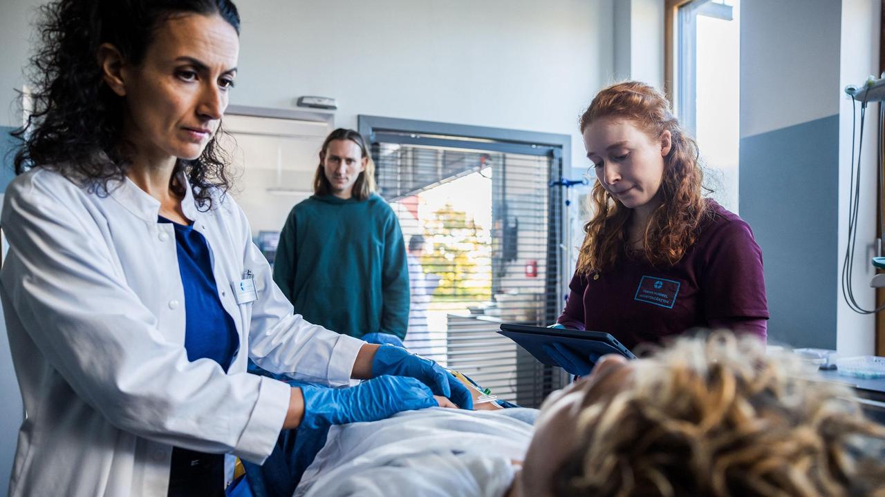 Dr. Leyla Sherbaz (Sanam Afrashteh) und Assistenzärztin Tamar Hummel (Linda Kummer) nehmen in der Notafnahme Lukas Schmitt (David Ali Rashed, vorne liegend) auf, der von seinem Sozialpädagogen Felix Hartung (Liliom Lewald) begleitet wird.