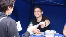 Stefan Ruppe überreicht einem Fan strahlend seine signierte Autogrammkarte.