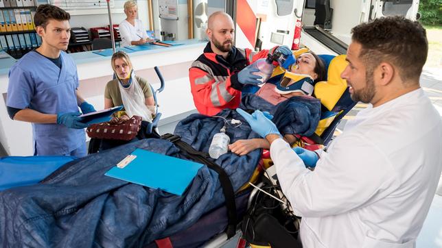 Heidi Kluttig (Merle Collet) bangt um das Leben ihrer Freundin Lena Schötz (2.v.r. mit Kompase). Dr. Matteo Moreau (Mike Adler) und Florian Osterwald (Lion Wasczyk) vermuten eine schwere Hirnverletztung bei der Patientin.