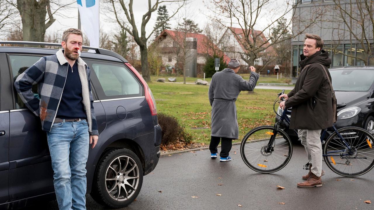 Marc Lindner (Christian Beermann) sammelt den verletzten Mario Pfeffer (Max Engelke) vor dem Eingang des Johannes-Thal-Klinikum auf (mit Komparse).