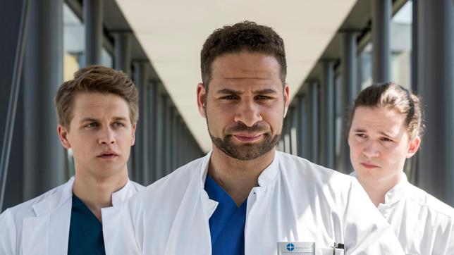 Moreau nimmt sich die beiden Neuen zur Brust und schickt sie zur Patientin Waltraud. Doch warum sollen sie deswegen in den Keller? V.l.n.r. Tom Zondek (Tilman Pörzgen), Dr. Matteo Moreau (Mike Adler), Mikko Rantala (Luan Gummich).