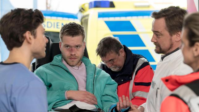 Bild: ARD/Jens-Ulrich Koch Nach einem Zusammenstoß mit einer Glastür nehmen Florian (Lion Wasczyk) und Marc (Christian Beermann, 2.v.r. mit Komparsin) Vincent Tülke (Antonije Stankovic, 2.v.l. mit Komparse) auf. Er ist bereits zum zweiten Mal innerhalb kurzer Zeit im Johannes-Thal-Klinikum.